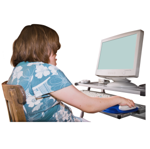 A young lady sat at her desktop computer and clicking her mouse.